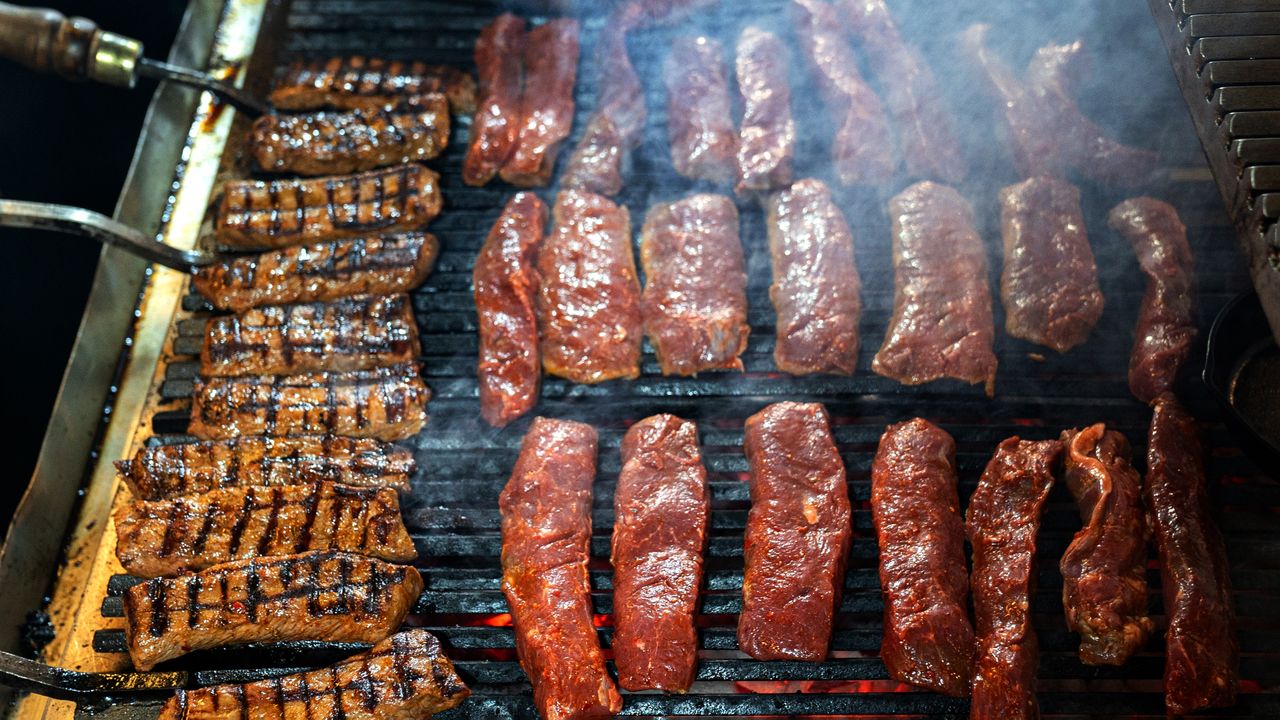 Juicy steaks being grilled outdoors, showcasing delicious char marks and smoke.